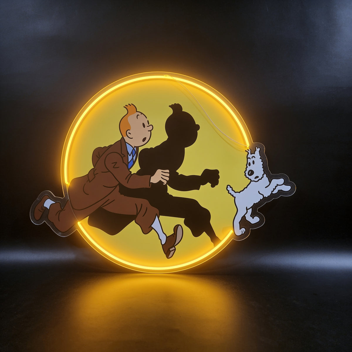 Neon artwork of a boy and dog running in front of a glowing yellow circle, shown on a dark wall.