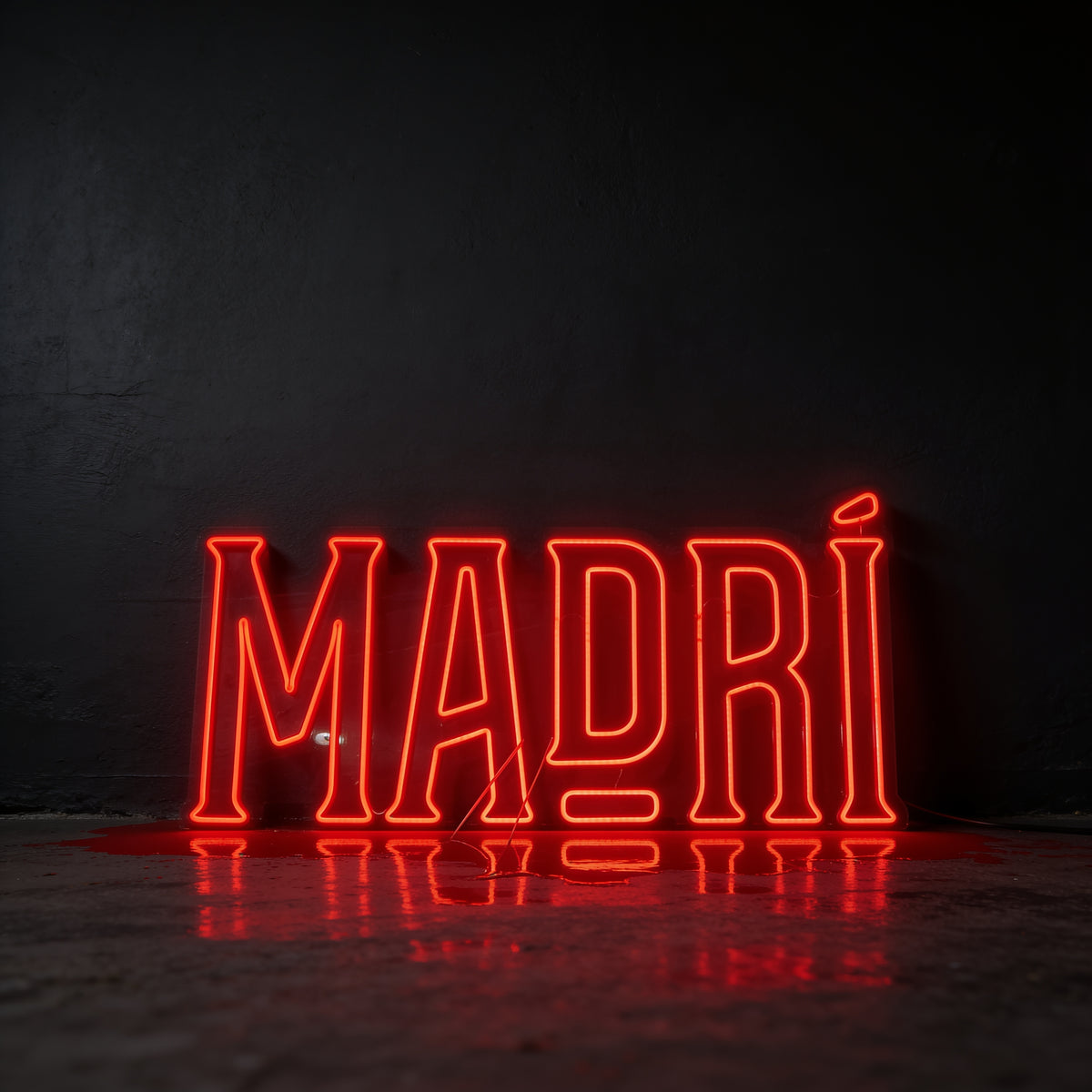 Red neon sign reading Madri, photographed against a dark wall.