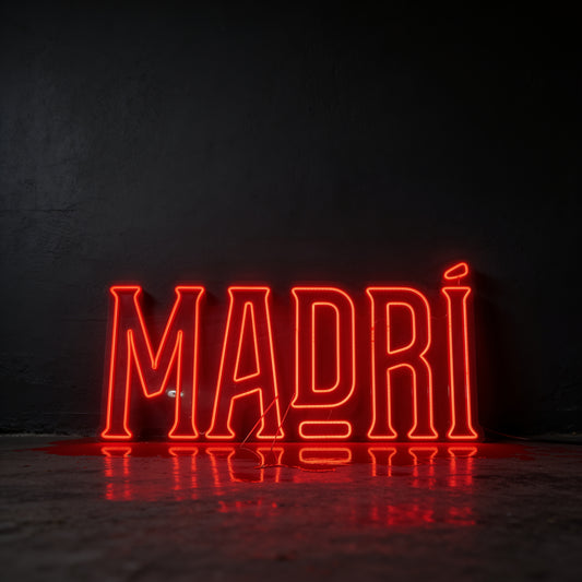 Red neon sign reading Madri, photographed against a dark wall.