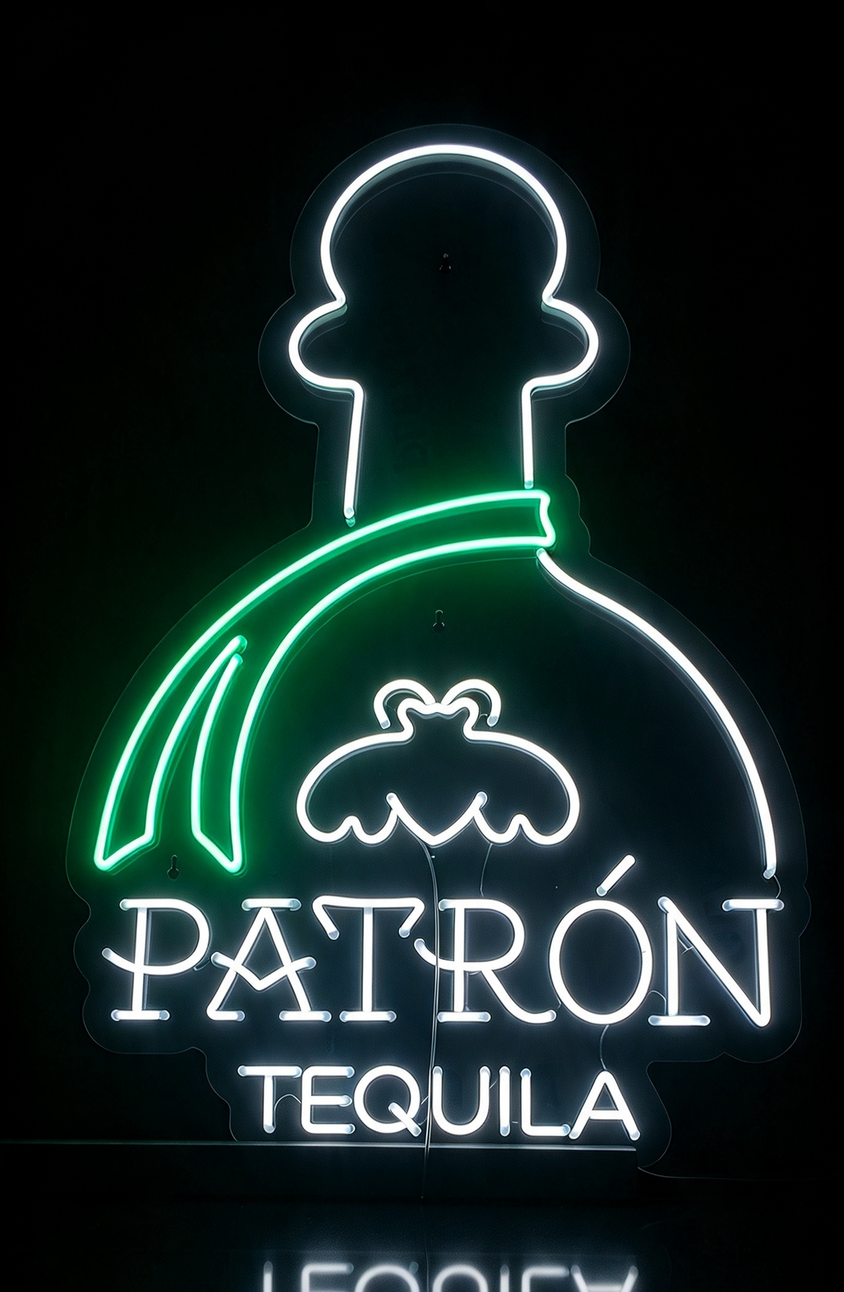 Green and white neon sign shaped like a bottle, reading Patrón Tequila, on a dark background.