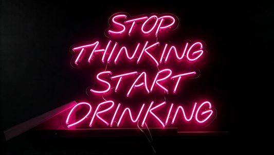 Pink neon sign reading “Stop Thinking Start Drinking” on a dark background.